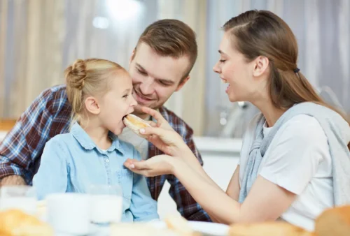 Parents feed their child a fresh pastry